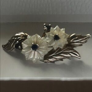 Vintage flower brooch with mother-of-pearl petals and sapphire centers.